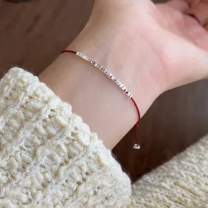 Minimalist S925 silver red string bracelet wrist detail shot, elegant Chinese style accessory.