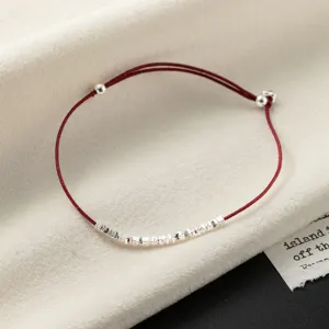 Close up of minimalist S925 silver beads red string bracelet detail, elegant design.