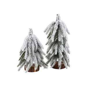 Mini snow-flocked cedar Christmas trees detail, artificial pine with natural wood base.