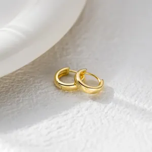 Nahaufnahme minimalistischer Gold-Creolen, mit glatter runder polierter Oberflaeche.