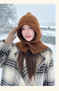 Detailed shot of a cozy brown knitted balaclava hooded scarf worn outdoors in winter snow.
