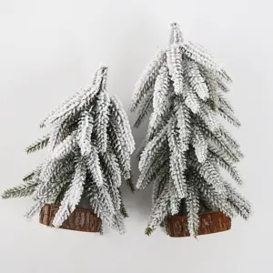 Close-up detail of mini artificial snow cedar Christmas tree with a natural wood log base.