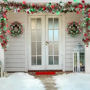 Christmas tinsel garland and wreaths hanging on white door for holiday party home decor scene.