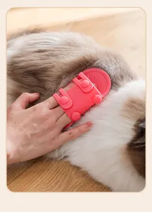 Silicone cat grooming brush detail showing hand wearing pink strap brushing pet fur safely.