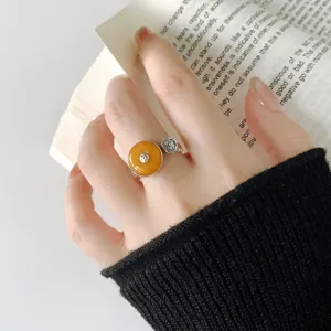Close-up detail of retro silver ring featuring amber coin and ruyi cloud design on hand model.