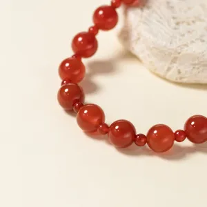 Detailaufnahme des eleganten roten Achatperlenarmbands mit polierter Edelsteinstruktur.