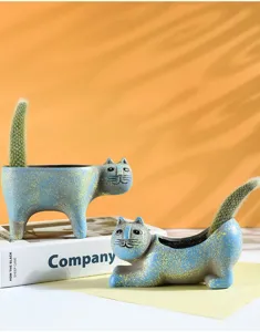 Detail view of cute ceramic cat flowerpot with cactus, vintage desktop green plant decor.