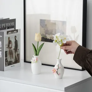 Nahaufnahme einer minimalistischen weißen Mini-Keramikvase mit handgefertigtem Blumendekor.