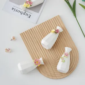 Detaillierte Nahaufnahme handgemachter Keramik-Minivasen mit filigranen 3D-Blumendesigns.