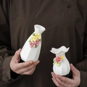 Nahaufnahme von handgefertigten Miniatur-Keramikvasen mit filigranem Blumendekor, in weiß.