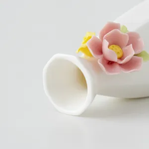 Nahaufnahme Detail der weißen Keramikvase mit filigranem handgefertigtem rosa Blumendekor.