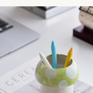 Leuke keramische paddenstoel penhouder op bureau, groene decoratieve opbergdoos met stippen.