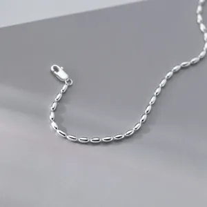 Gedetailleerd close-up van een zilveren armband met olijfkrralen en fijne heldere metaalglans.