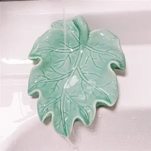 Detail view of green leaf shaped soap dish in sink, showing drainage features and unique design.
