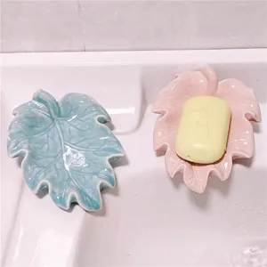Detail shot of ceramic leaf soap dish placed on white basin with yellow soap for bathroom decor.