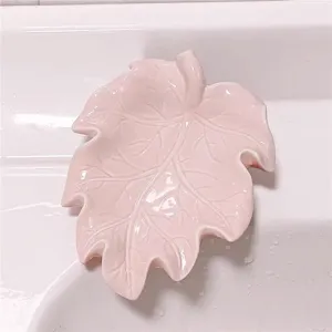 Pink leaf-shaped soap dish, ceramic or plastic soap holder for bathroom sink drainage.