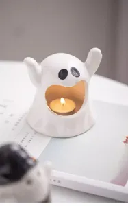 Gros plan d'un mignon bougeoir fantôme en céramique avec doublure dorée et douce lumière.