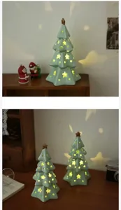 Ceramic Christmas tree night light detail shot showing warm star glow on wooden table.