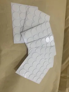Close-up detail of white round double-sided adhesive glue dots, sheet packaging display.