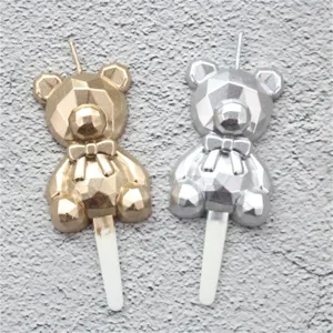 Detailed view of gold and silver geometric faceted bear birthday candles for party decor.