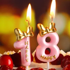 Pink number birthday candles with gold bow design, perfect cake decoration for party celebrations.