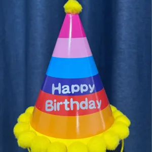 Colorful children's birthday party conical hat close-up, cute yellow pom-pom detail.
