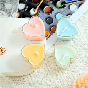 Gros plan de bougies parfumées en forme de cœur coloré dans des supports transparents.