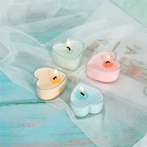Vue détaillée de quatre bougies parfumées colorées en forme de cœur dans des tasses.