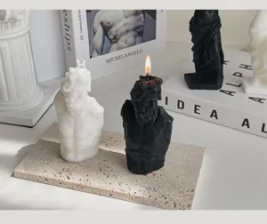 Dettaglio di candele profumate a forma di scultura greca in bianco e nero su vassoio di pietra.