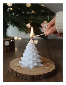 Primo piano di una candela profumata albero di Natale bianca accesa su base di legno.