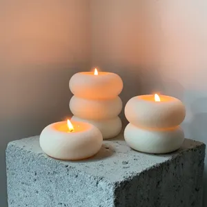 Gros plan de bougies parfumées circulaires créatives brillant doucement sur un bloc de béton.