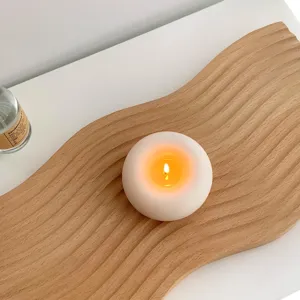 Bougie parfumée donut blanche minimaliste brûlant sur un plateau en bois pour décor cosy.