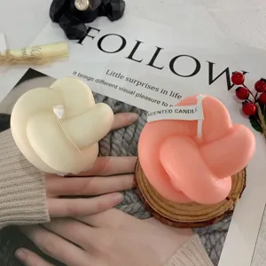 Detailaufnahme ästhetischer Knoten-Duftkerzen in Weiß und Rosa auf Hand präsentiert.