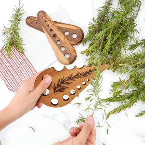 Wooden herb stripper tool with multiple holes for stripping rosemary and thyme leaves easily.