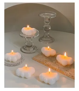 Witte wolk geurkaarsen detail op glazen houders en stenen blad met gezellige warme sfeerverlichting.