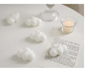 Detailopname van witte wolk geurkaarsen op een minimalistische tafel met mooie rekwisieten.