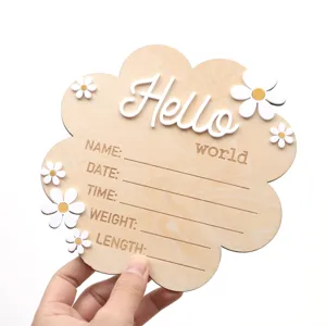 Close-up detail of the wooden baby milestone card with engraved hello world text and cute flowers.