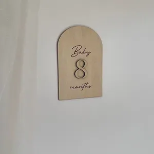 Dettaglio supporto foto pietra miliare mensile neonato in legno, design arco minimalista.