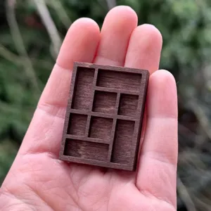 Close up detail of miniature wooden trinket shelf showing compartments and fine wood texture.