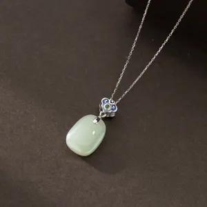 Close-up of elegant oval green jade pendant with sterling silver chain and vintage blue enamel cloud bail.