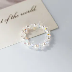 Close-up of sparkling AB crystal and faux pearl beaded ring detail, delicate design.