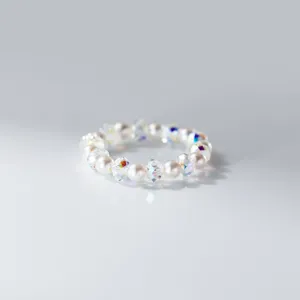 Detailed close-up of iridescent crystal and pearl beaded ring, shimmering details, chic design