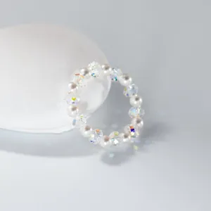 Detail shot of a minimalist crystal and pearl beaded ring, sparkling iridescent design.