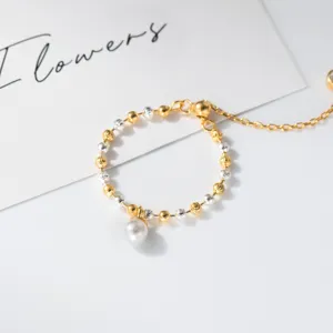 Gros plan d'un délicat anneau de perles bicolore avec chaîne réglable et pendentif perle.