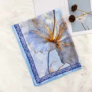 Close-up detail of blue floral print silk scarf fabric texture, elegant and lightweight shawl.