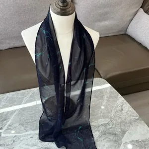 Detailansicht des dunkelblauen Chiffonschals mit turkisen abstrakten Linien auf der Puppe.