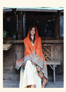 Vista detallada del poncho con capucha de mujer estilo étnico con rayas naranjas y azules.