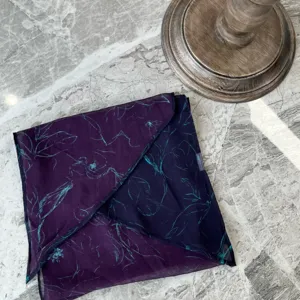 Detailaufnahme eines dunkelvioletten Damenschals mit abstraktem blauem Blumenmuster, feine Textur.