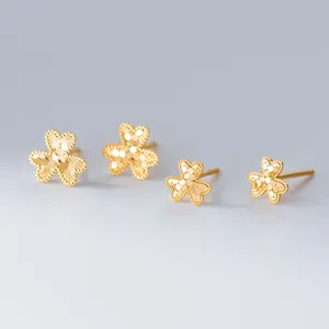 Detaillierte Nahaufnahme von eleganten Gold-Kleeblatt-Ohrsteckern mit strukturierter Oberfläche.