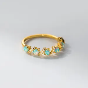 Detailansicht eines eleganten goldenen Opal-Wickelrings mit funkelnden Zirkonias.